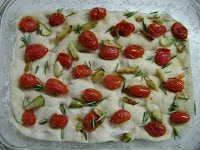 tomatoes and garlic on focaccia dough.