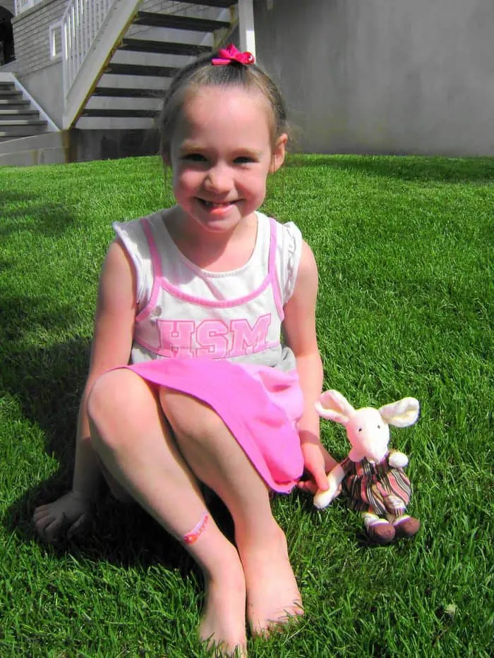 jelly cat mouse plush sitting on grass next to little girl