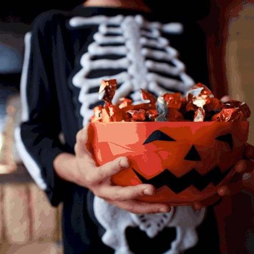 Boy holding a bowl with Halloween sweets