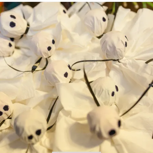 DIY spooky Tootsie Pop Ghosts with white kleenex and black marker for Halloween party treats.