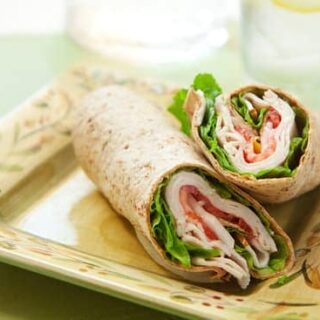 Turkey wrap with lettuce and tomatoes on a square plate