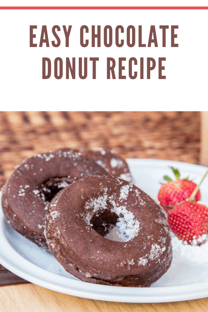 fresh chocolate cake donuts sprinkled with sugar with strawberry garnish on plate