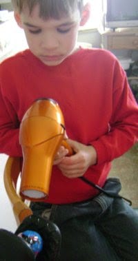 boy using hair dryer for paas egg.