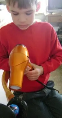 boy using hair dryer for paas egg.