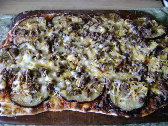 Grilled pizza with eggplant, basil, and cheese on a BBQ grill for a smoky, crispy crust