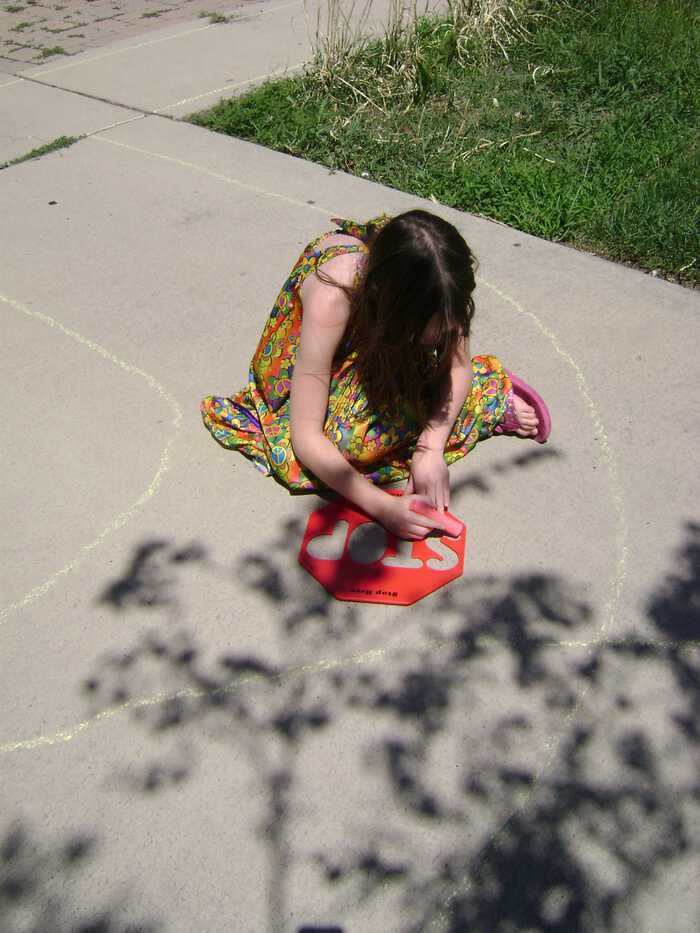 city chalk girl stenciling stop sign with sidewalk chalk