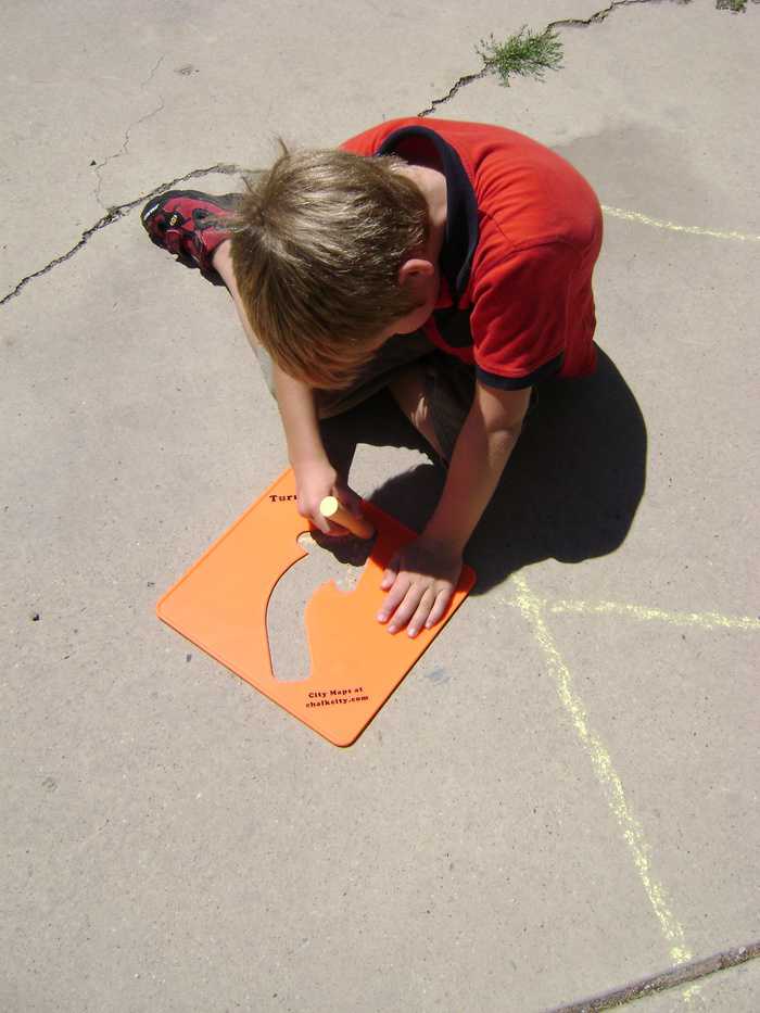 boy using stencil and side walk chalk for right turn