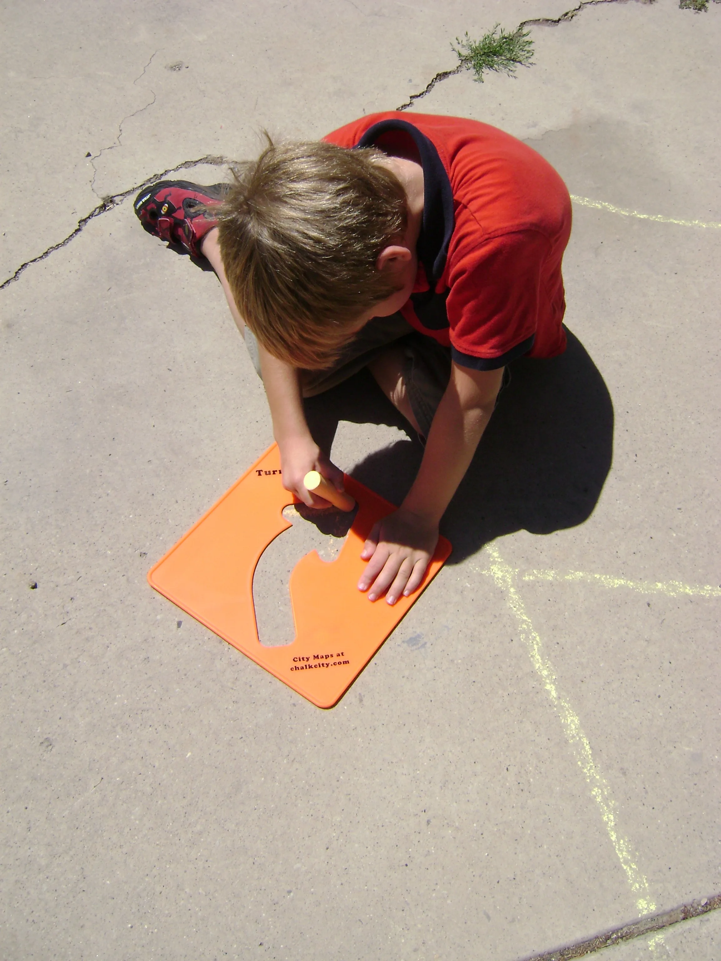 boy using stencil and side walk chalk for right turn