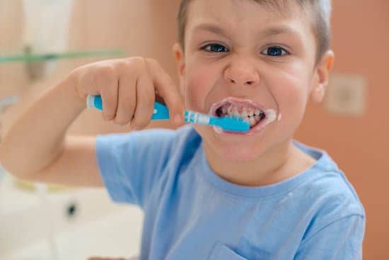 Happy kid or child brushing teeth in bathroom. Dental hygiene.