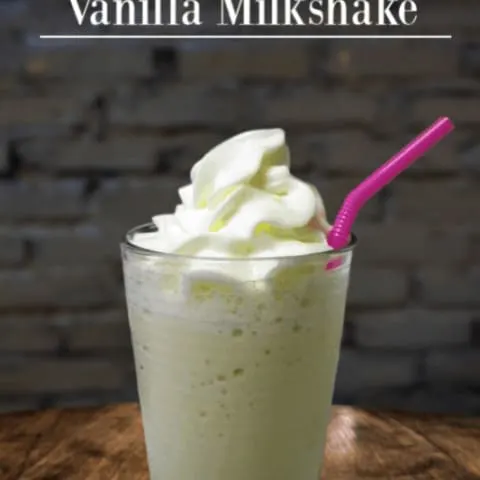 homemade easy vanilla milkshake on wood table with pink straw and brick background