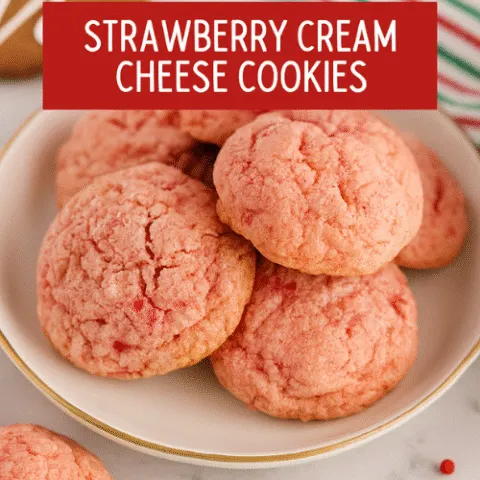 A holiday-themed plate of strawberry cream cheese cookies styled with red and green accents, powdered sugar garnish, and festive decorations. The cookies are pink, soft, and cracked on top, photographed with macro clarity for a cozy, cheerful Christmas vibe.