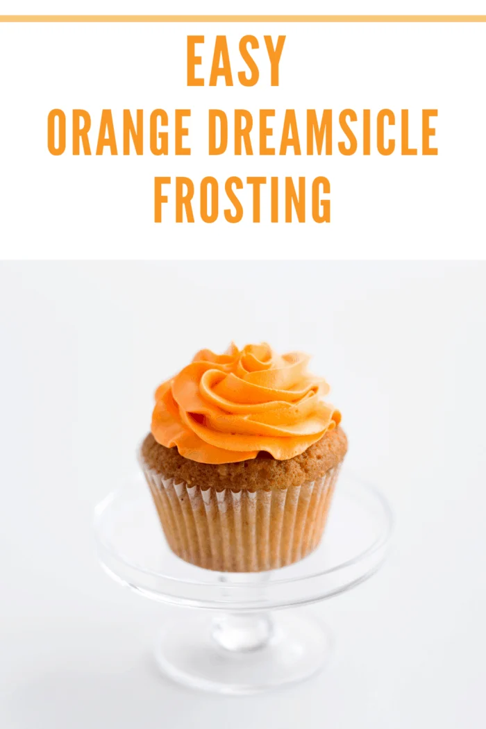 A single cupcake with beautifully piped orange dreamsicle buttercream frosting on top.