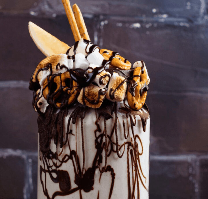 toasted marhmallow milkshake with pretzel embellisments and chocolate syrup on grunge vintage background.