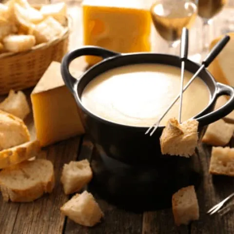 cheese fondue with fondue fork resting on pot with bread piece on end