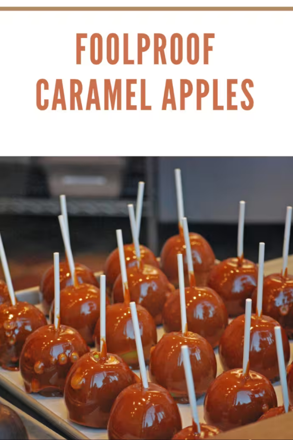 Homemade caramel apples on a baking sheet, featuring a smooth caramel coating for a delicious fall dessert.