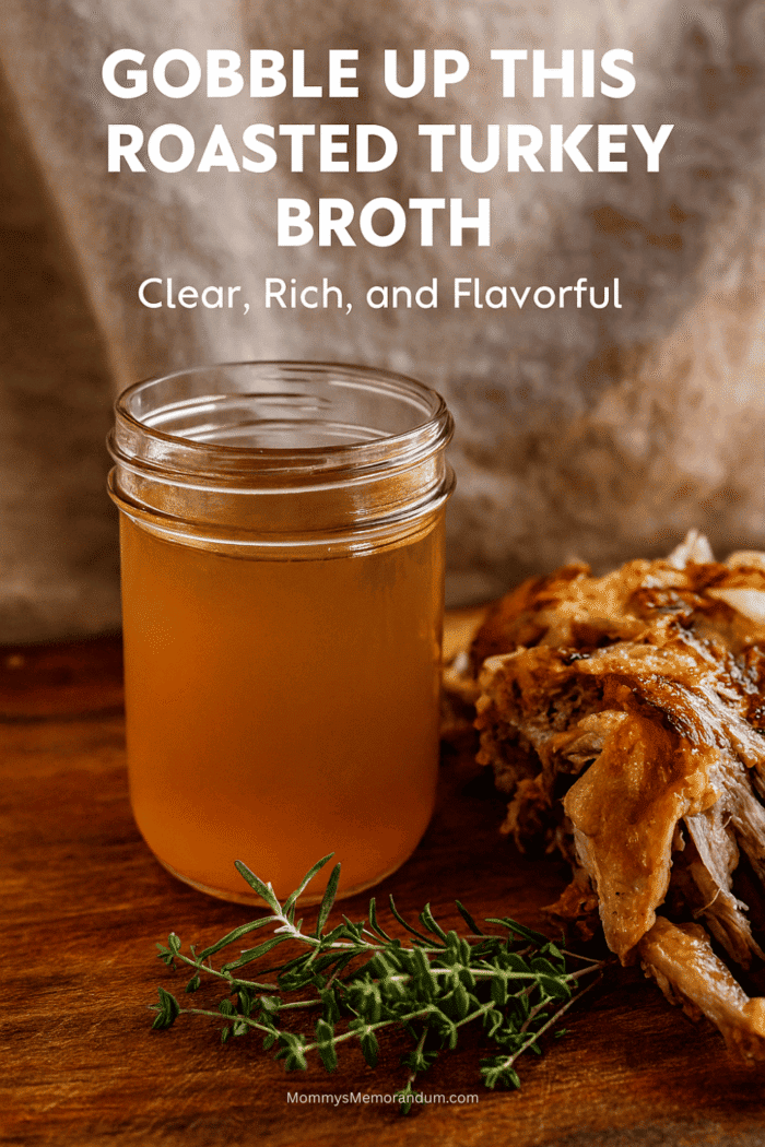 Clear roasted turkey broth in a mason jar with herbs and turkey bones on a rustic wooden table
