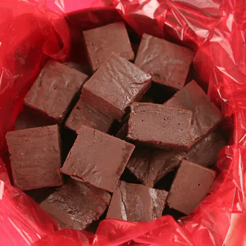 a closeup of homemade kahlua fudge in a holiday tin for gift giving.