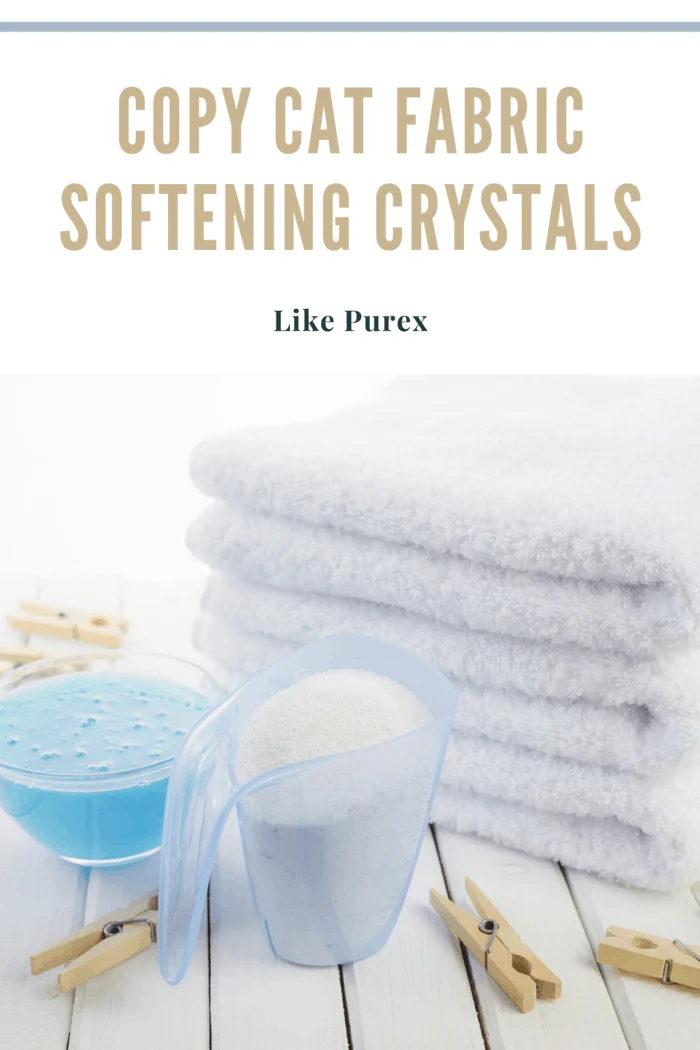 homemade fabric softening crystals in container next to clean white towels that are folded