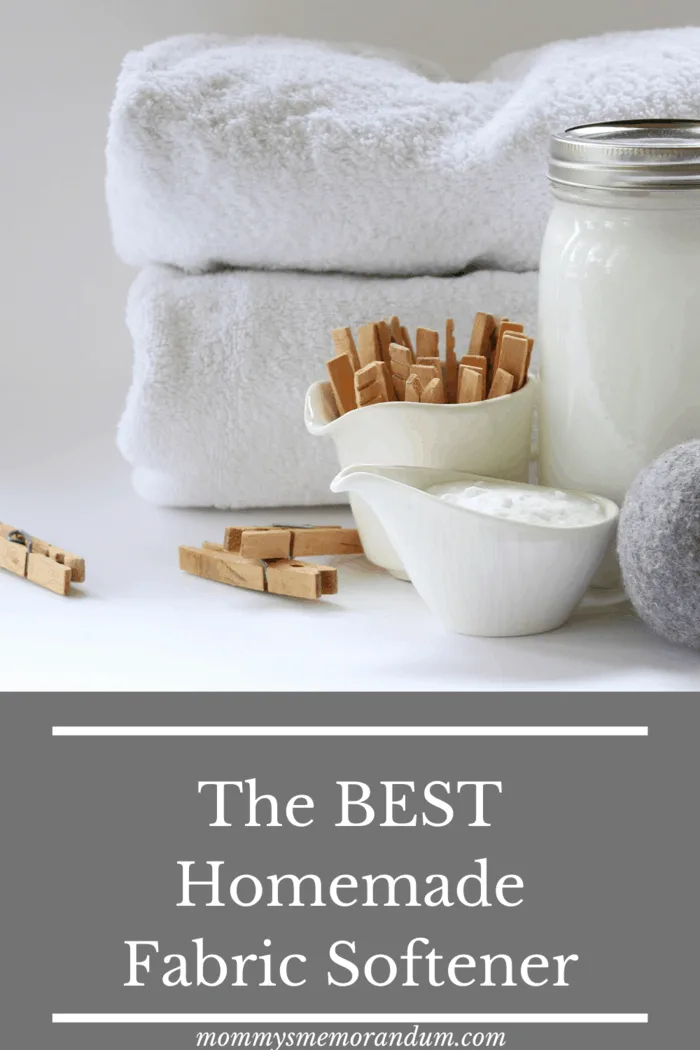 white fluffy towels folded with clothes pins, wool dryer balls and homemade fabric softener in large mason jar