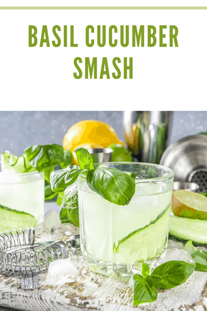 Refreshing basil cucumber smash cocktail garnished with fresh basil leaves and cucumber slices, served on a rustic wooden table.