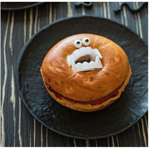 A Halloween-themed bagel with plastic fangs and candy eyes, a spooky and fun PB&J snack for kids