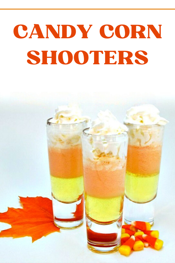 Layered candy corn shooters topped with whipped cream, featuring festive Halloween colors and sweet flavors