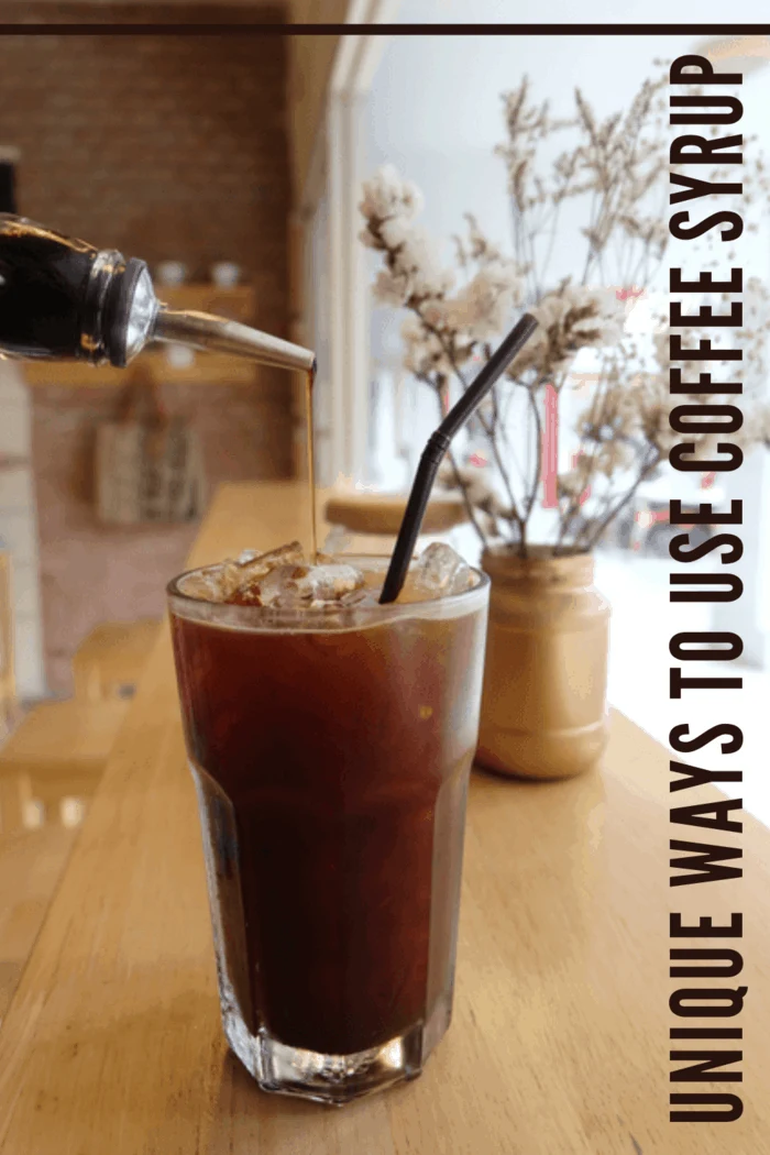 Coffee syrup being poured into a glass of iced coffee, adding a rich flavor to the drink in a cozy café setting.