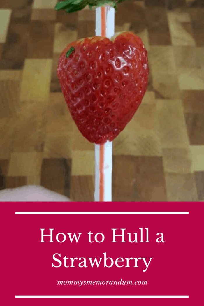 removing the stem of a strawberry with a straw