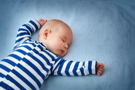 baby in navy and white sleeper sleeping on blue blanket