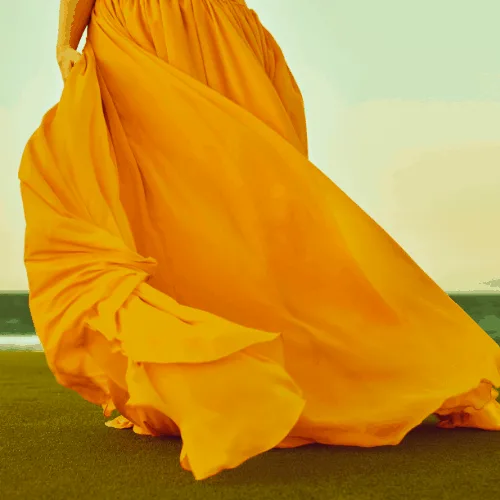 unrecognizable woman in summer time with yellow chiffon dress flying all around.
