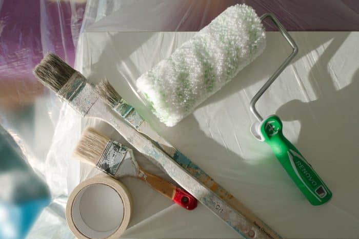 paint brushes with paint roller and tape overhead view
