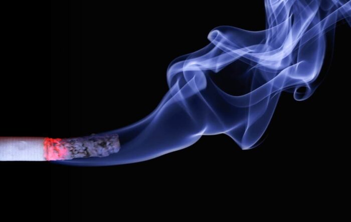 cigarette with blue smoke on black background