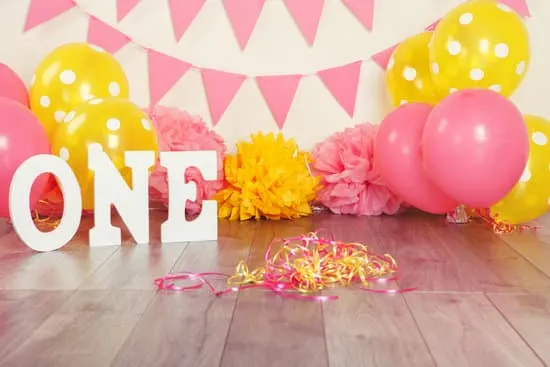 Festive background decoration for birthday celebration with letters saying one and pink red yellow balloons in studio. Cake smash first year concept.