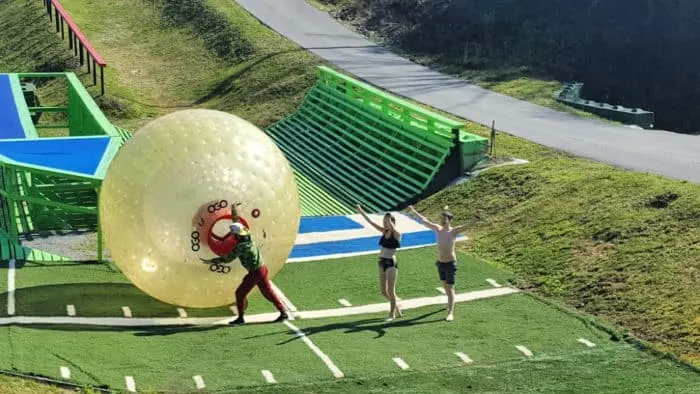 Two people finishing a zorbing run at Outdoor Gravity Park in Pigeon Forge, TN, with an instructor assisting