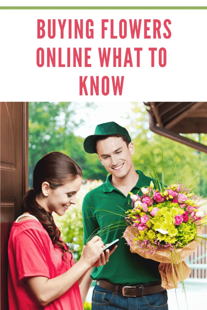 Smiling delivery man delivering a bouquet of flowers for young woman, standing in th entrance house door and woman signing up on the palmtop.