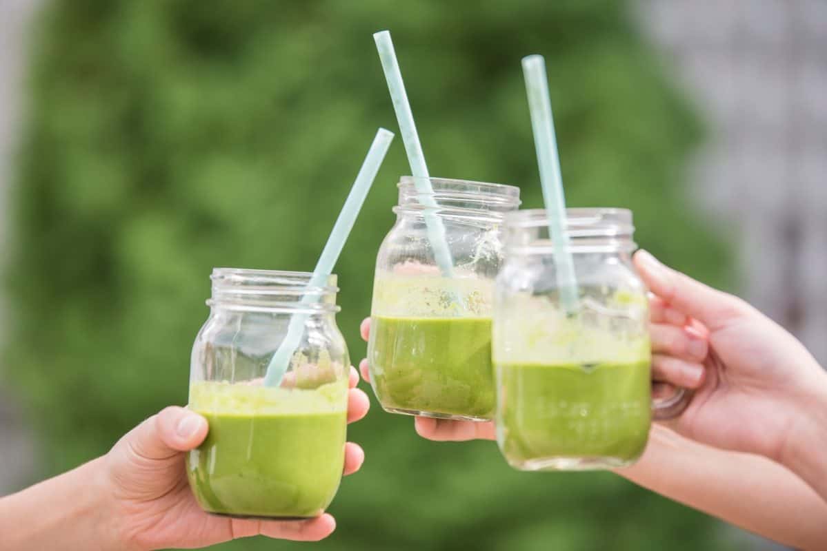 green smoothie in mason jars with straws