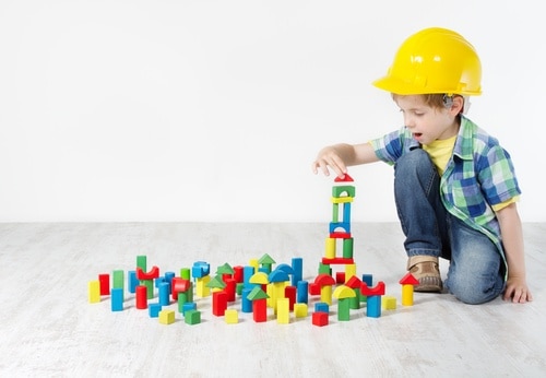 child with yellow hard hat playing with color blocks