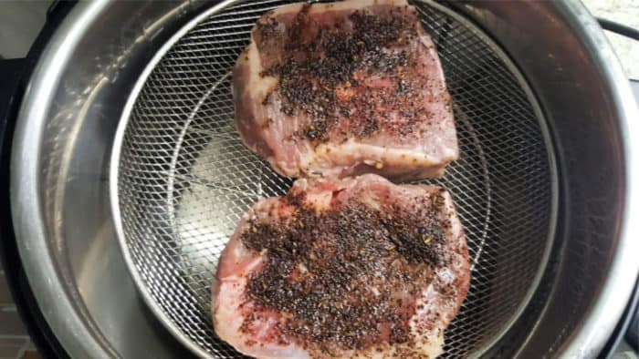 add seasoned ribeye steaks to mesh basket