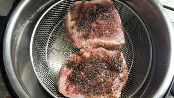 add seasoned ribeye steaks to mesh basket