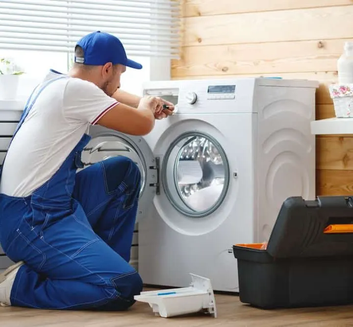 repairman doing appliance repair on washing machine