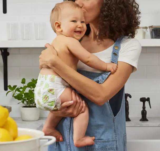 Woman holding and kissing baby, representing the benefits of a keto diet for new mothers' postpartum weight loss.