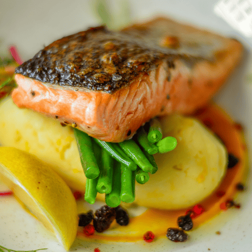 grilled smoked salmon on top of greens on white plate