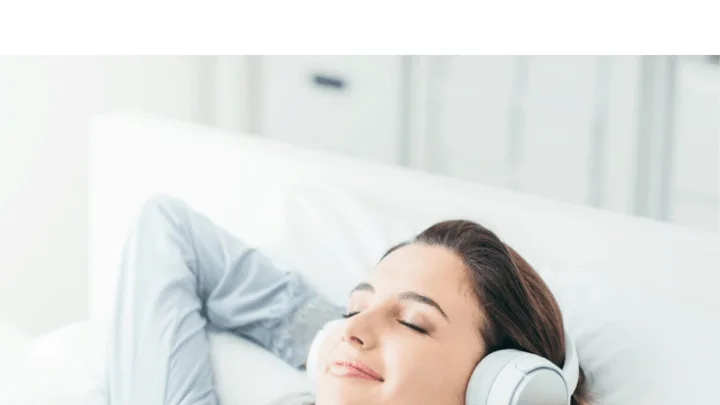 woman on bed listening to music through headphones before sleeping