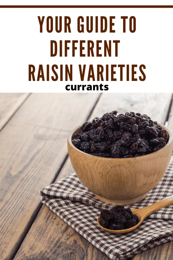 Wooden bowl filled with currants on a rustic table, highlighting different raisin varieties.