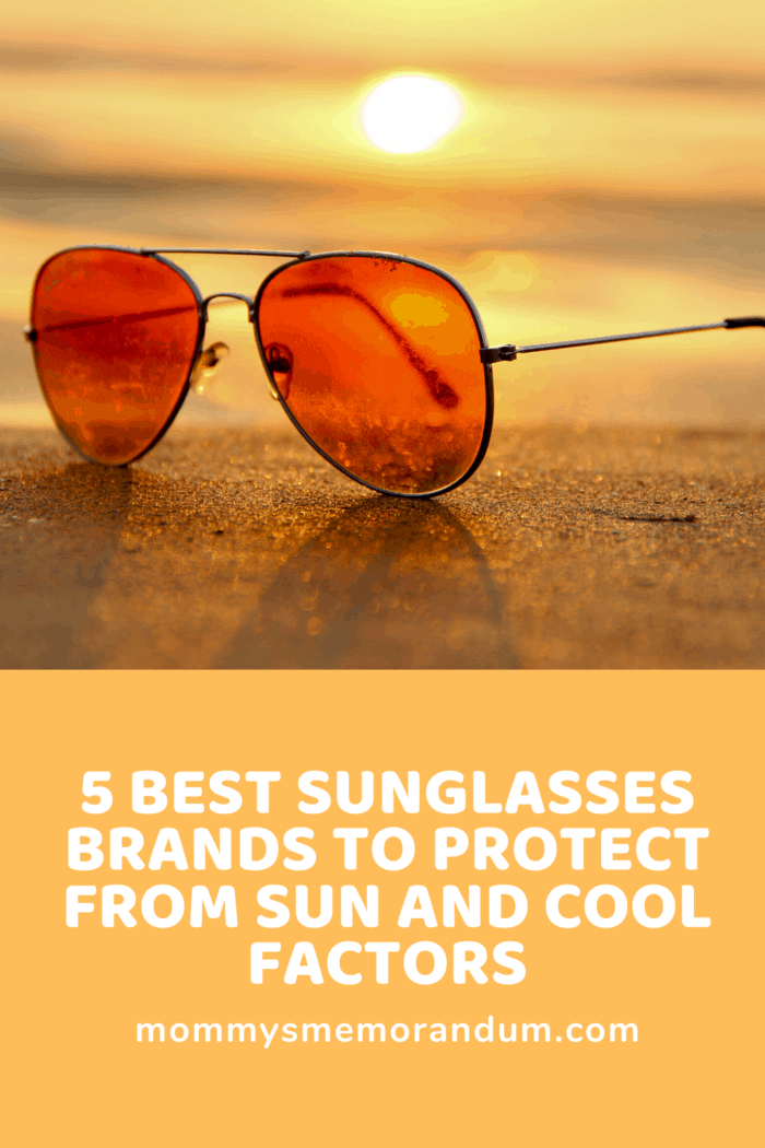 pair of name brand sunglasses on the sand on a beach at sunset