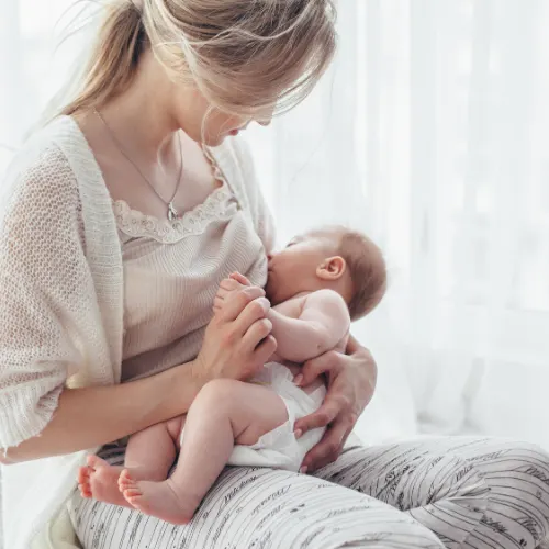 Bright portrait of a mom breast feeding baby over window lighting.