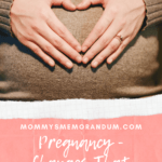 pregnant woman in brown sweater with hands making heart on belly
