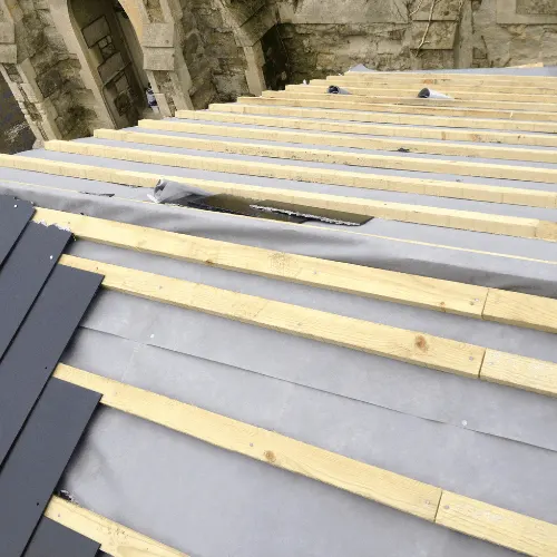 Image shows a roof being replaced with new tiles, felt and batten.
