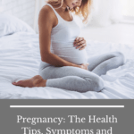 pregnant woman sitting on white bed holding stomach