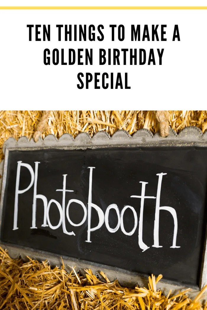 A decorative photobooth sign in a rustic setting with straw, perfect for capturing memorable moments at a golden birthday party.